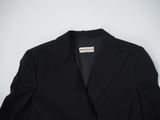 a black blazer jacket on a hanger against a white wall