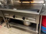 une grande cuisinière dans une cuisine, sur laquelle sont posés de nombreux plats