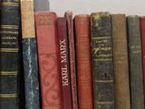several old books are lined up on a shelf in front of a white wall