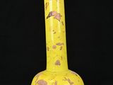 un vase jaune posé sur une surface noire