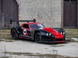une voiture de course rouge et noire garée devant un immeuble
