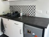 une petite cuisine équipée d'un réfrigérateur, d'un évier et d'un micro-ondes