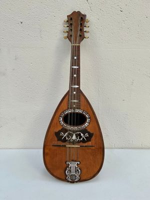 une vieille mandoline en bois posée sur une table blanche