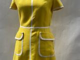 yellow dress with white trim on mannequin base in front of a white backdrop