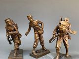 three bronze figurines of soldiers with guns and helmets