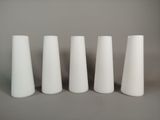four white vases are lined up in a row on a gray surface