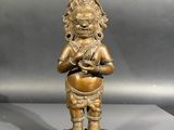 une statue antique en bronze représentant une personne tenant un pot