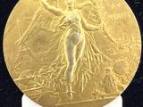 une image montrant un gros plan d'une médaille d'or posée sur une surface noire