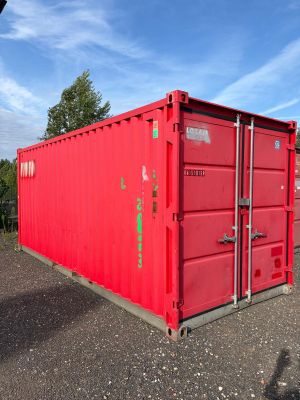 red shipping container sitting in a parking lot on a sunny day