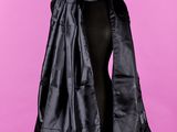une femme portant une cape noire, un haut noir et un pantalon noir