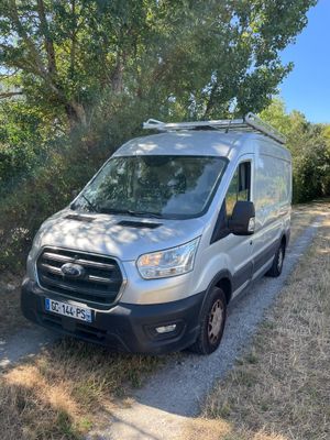 une camionnette argentée garée sur un chemin de terre, près des arbres