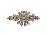 un gros plan d'une broche en forme de fleur sertie de diamants, sur fond blanc