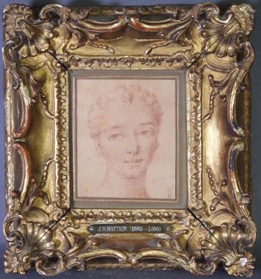 On y voit une vieille photo représentant le visage d'une femme, encadrée dans un cadre doré.