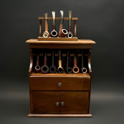 une armoire en bois surmontée d'une série de porte-pipes
