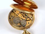 a gold pocket watch with a chain hanging from it ' s side