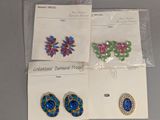 Trois paires de boucles d'oreilles et des broches sont exposées sur une table