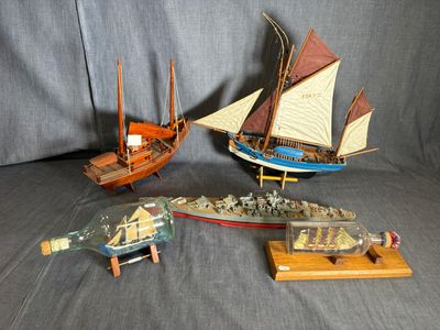 trois bateaux miniatures et une bouteille posés sur une table
