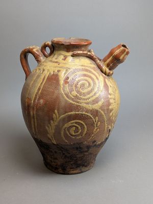 a brown and yellow vase sitting on a gray surface