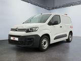 La camionnette blanche est garée dans une grande pièce au sol noir.