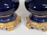 pair of blue and gold table lamps on pedestals on a white surface