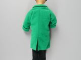 a close up of a doll wearing a green coat and black pants