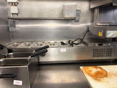 stainless steel counter top in a commercial kitchen with a pizza on a cutting board