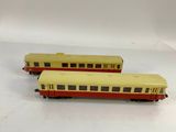 two yellow and red train cars sitting on top of a white surface