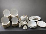 a lot of white and gold plates and bowls on a table