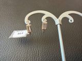 une paire de boucles d'oreilles sur un bâtonnet, avec une étiquette de prix accrochée dessus