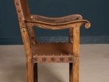 an old wooden chair with a leather seat and arm rest