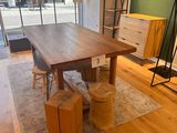 une table en bois au milieu d'une pièce, avec des mannequins en arrière-plan
