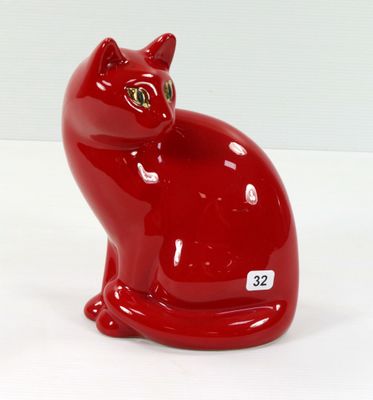une figurine de chat rouge posée sur une surface blanche