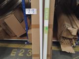 une pile de cartons et un tube blanc posés sur une étagère