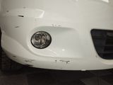 the front end of a white car with a dented bumper