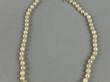 a white pearl necklace with a gold clasp