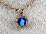 a close up of a gold chain with a blue glass pendant on it