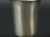 une coupe ancienne en argent posée sur un socle, sur fond noir