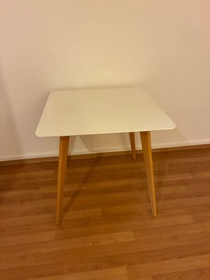 une table blanche aux pieds en bois, dans un coin de la pièce