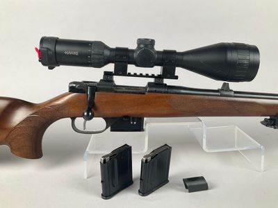 a close up of a rifle with a scope on a white background