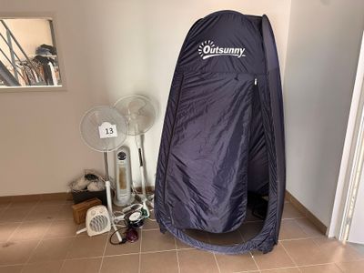 une tente bleue installée dans un coin de la pièce, à côté d'un ventilateur