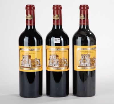 trois bouteilles de vin rouge posées l'une à côté de l'autre sur une surface blanche