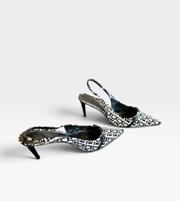 une paire de chaussures en peau de serpent noire et blanche posées sur une surface blanche