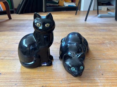 deux chats noirs assis l'un à côté de l'autre sur un plancher en bois