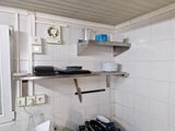 a small kitchen with a sink, stove, and shelves