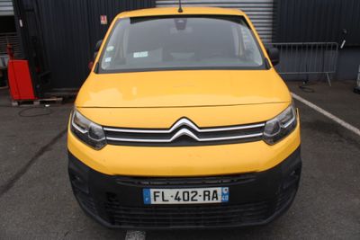 une camionnette Citroën jaune garée sur un parking devant un immeuble