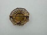 a close up of a gold brooch on a white surface