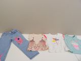 Plusieurs vêtements d'enfants sont alignés sur une table blanche