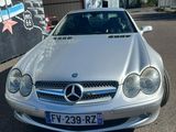 Une Mercedes Classe SL Coupé de couleur argentée garée devant un immeuble