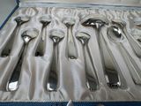 six silver spoons in a case on a table