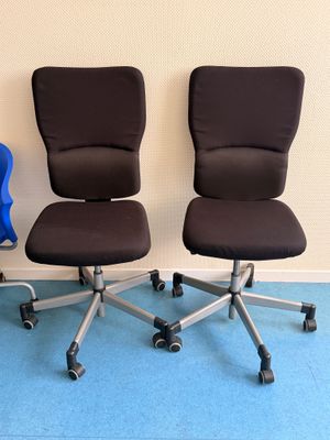 Trois chaises de bureau sont alignées contre un mur dans une pièce